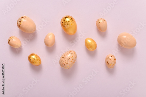 Easter background with painted eggs and sequins. Copy space. Flat lay, top view