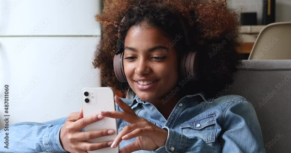 Cute curly haired African teenage girl wear wireless headphones wave ...