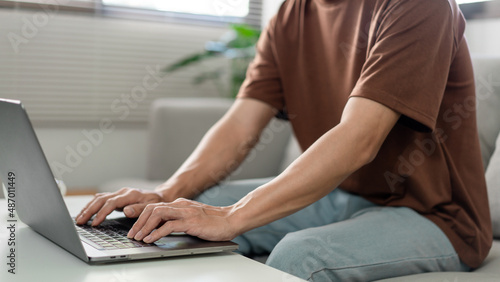 Technology Concept The man in brown T-shirt concentrating on typing something on his computer laptop