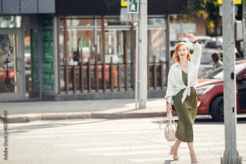 A red-haired woman in the city center, walking down the street © irinashamanaeva