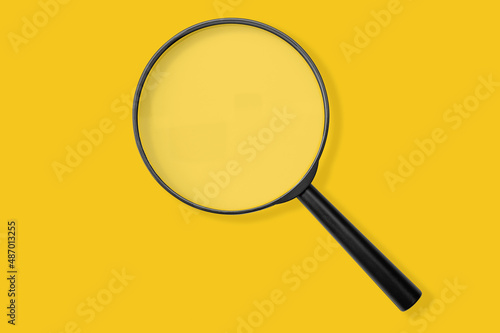 Magnifying glass black color isolated on yellow. Research, searching sale or investigating something. top view photo