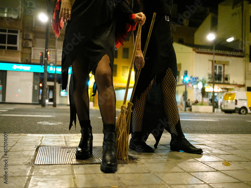Front view of legs of two young women dressed as witches for Halloween on the streets of Valencia, Spain.