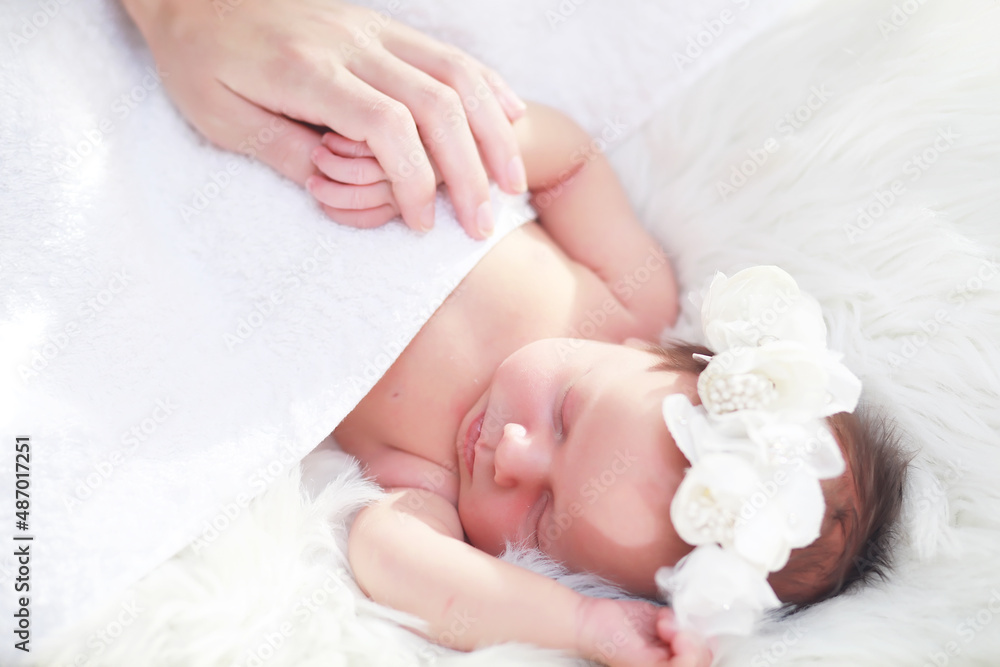 A newborn baby lies in her mother's arms. A beautiful baby of European appearance is sleeping. A newborn baby lies in her mother's arms. A beautiful baby of European appearance is sleeping.