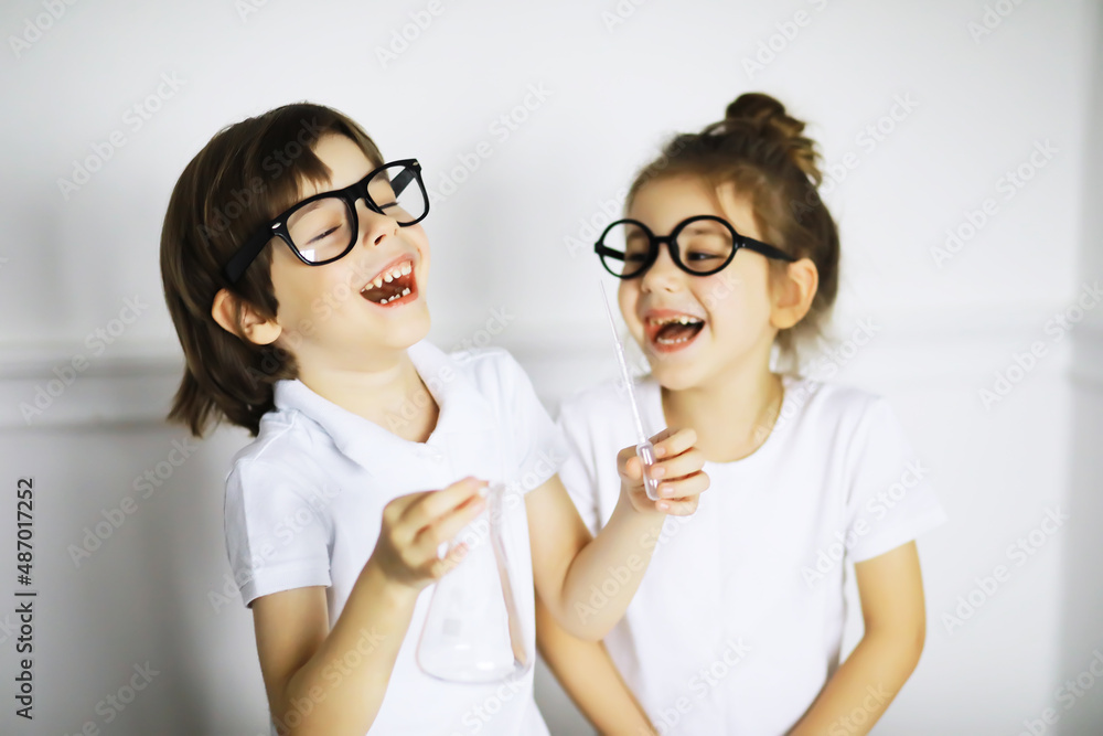 Two cute children at chemistry lesson making experiments on white background Two cute children at chemistry lesson making experiments on white background