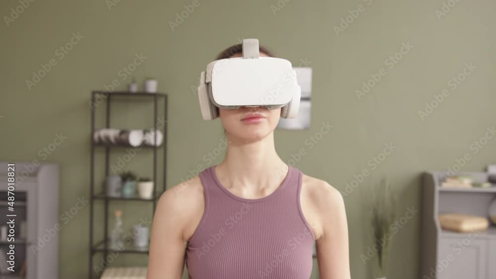 Slowmo shot of young active woman with bionic arm wearing VR headset while doing exercises at home Slowmo shot of young active woman with bionic arm wearing VR headset while doing exercises at home