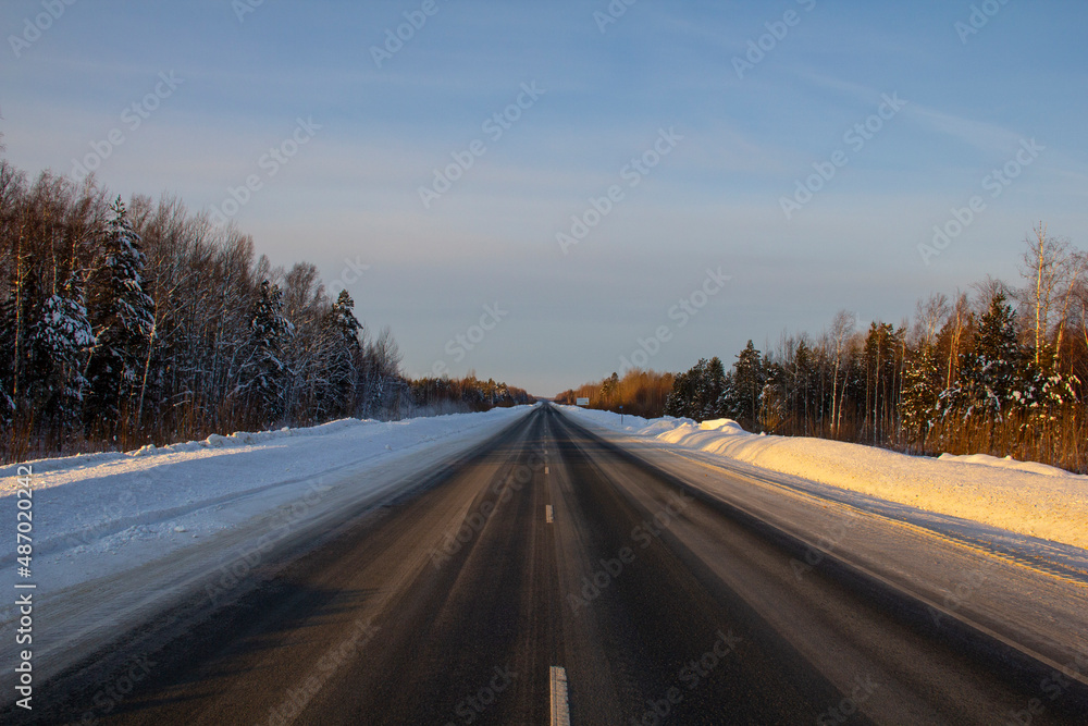 Winter track in the Siberian taiga. An icy winter highway runs through the snow and taiga. A section of the highway in the Khanty-Mansi Autonomous Okrug - Yugra between Khanty-Mansiysk and the city of