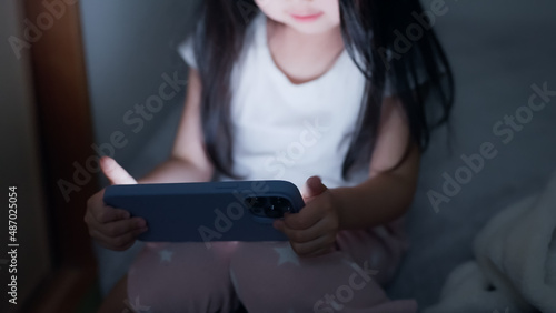 夜に暗い部屋でスマホを見る4歳の子供