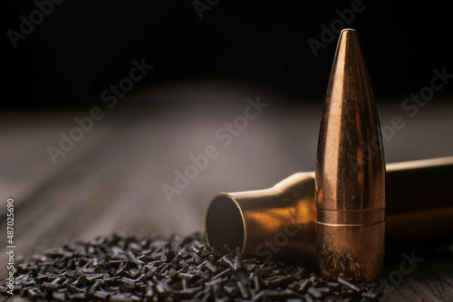 Macro shot of cartridge case, bullet and gunpowder on wooden background, soft focus