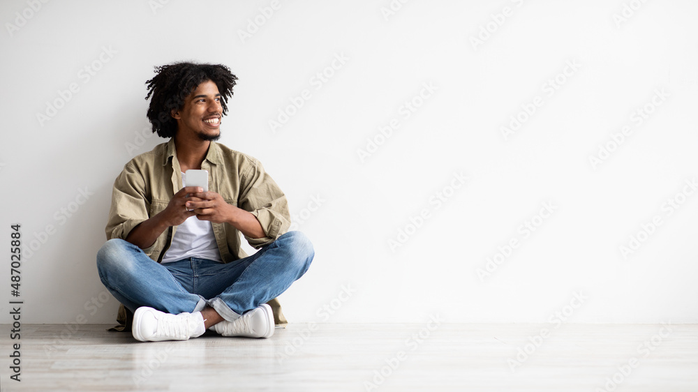 Online Offer. Smiling African American Guy Holding Smartphone And Looking Aside