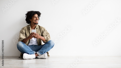 Online Offer. Smiling African American Guy Holding Smartphone And Looking Aside © Prostock-studio