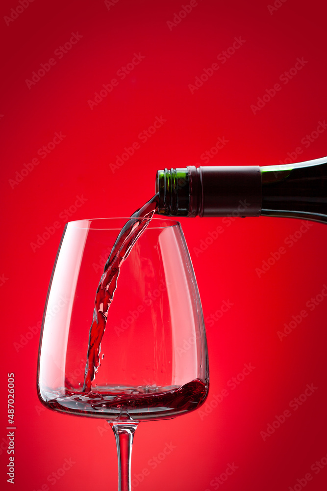 Fototapeta premium Red wine pouring from bottle into glass