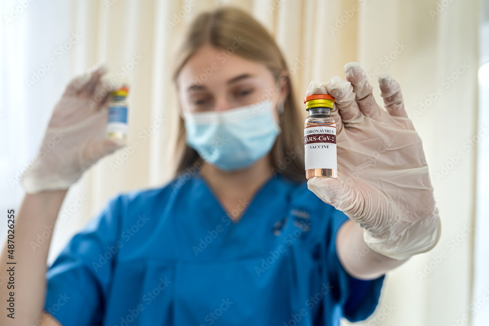 young charming nurse in gloves and mask draws a vaccine with a syringe for vaccination. young charming nurse in gloves and mask draws a vaccine with a syringe for vaccination.