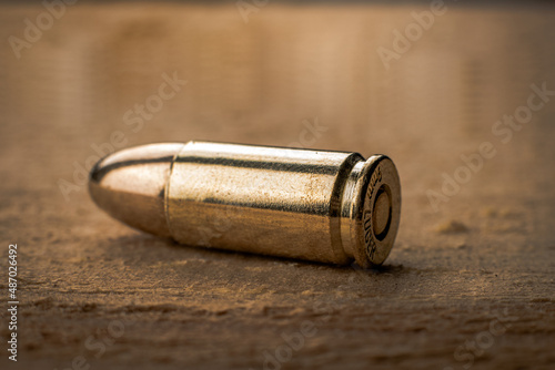 Macro shot of a pistol cartridge on a freshly cut wood texture, limited depth of field, soft focus