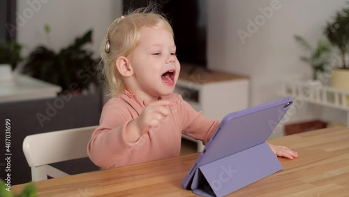 Concept of hearing impairment and their treatment. Cute little girl with a Cochlear implant using tablet PC photo