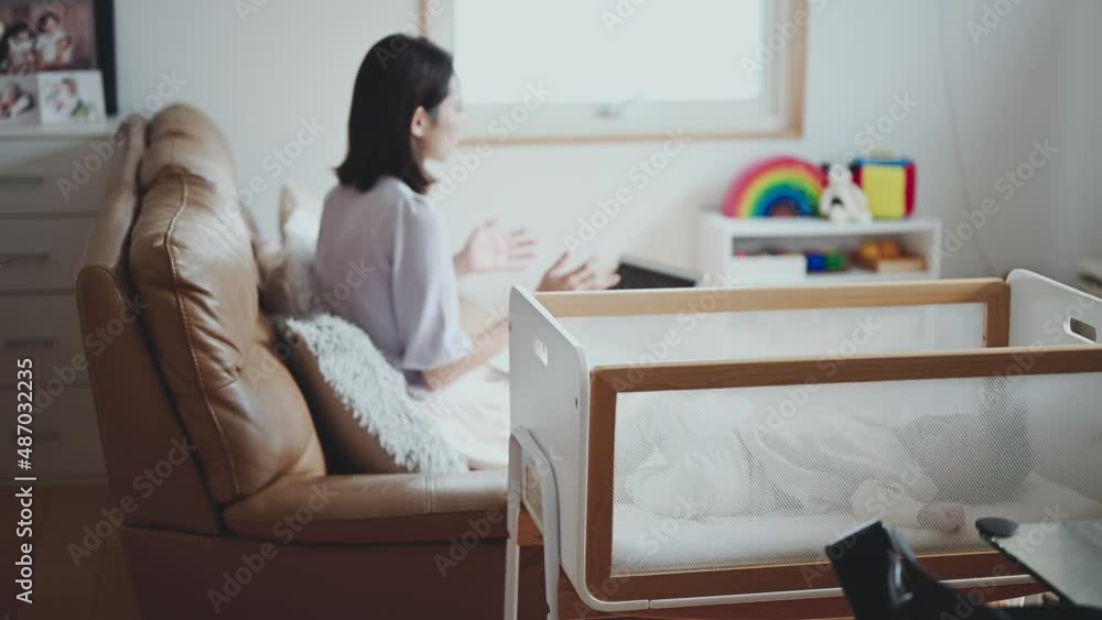 赤ちゃんのいるリビングでオンライン会議に参加するキャリア女性 赤ちゃんのいるリビングでオンライン会議に参加するキャリア女性