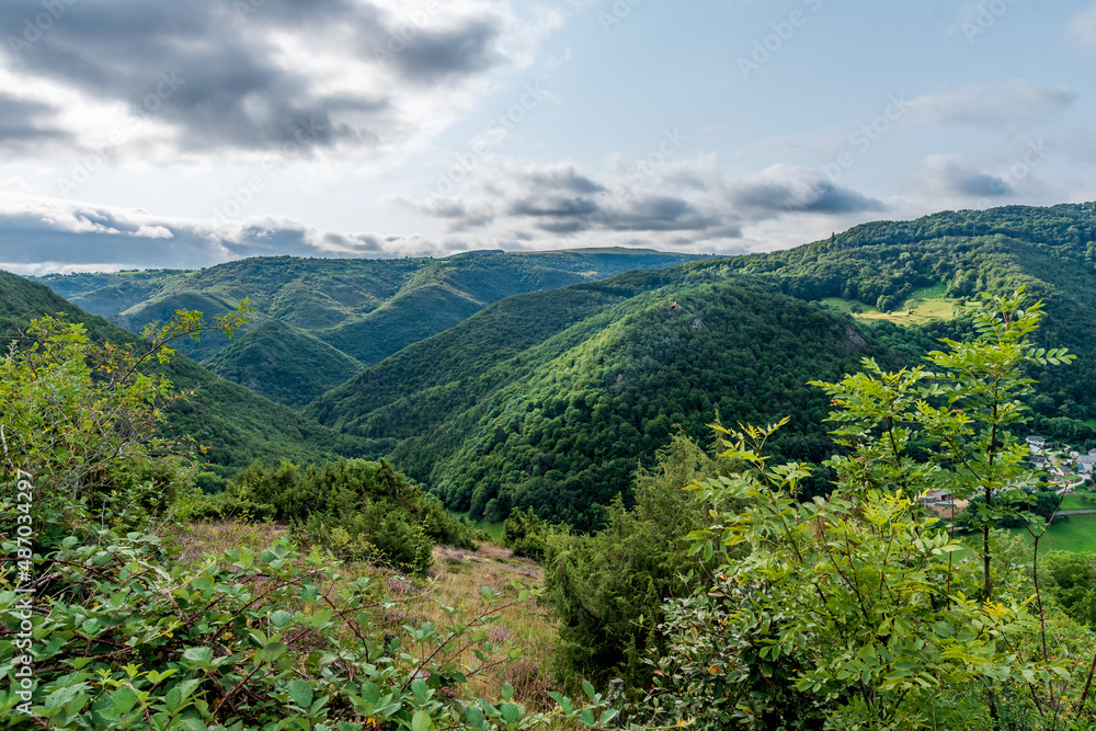 Fototapeta premium Panorama sur les montagnes recouvertes de forets pris depuis le sentier au loups et dominant la vallée de Courgoul dans le puy de dôme en Auvergne par une journée orageuse