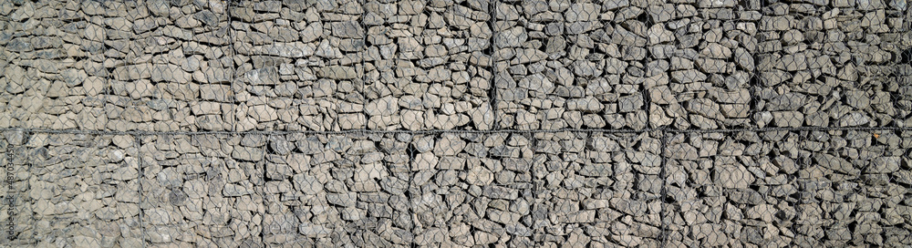 grey stone and pebbles in wire mesh wall horizontal stones facade background in panoramic web header grey stone and pebbles in wire mesh wall horizontal stones facade background in panoramic web header