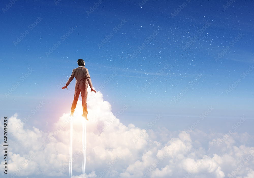 Businessman in suit and aviator hat flying in sky