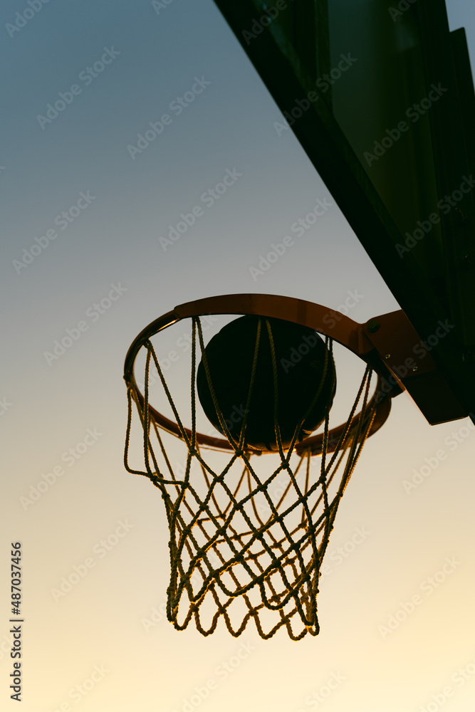 Silhouette of basketball at sunset, scoring point 