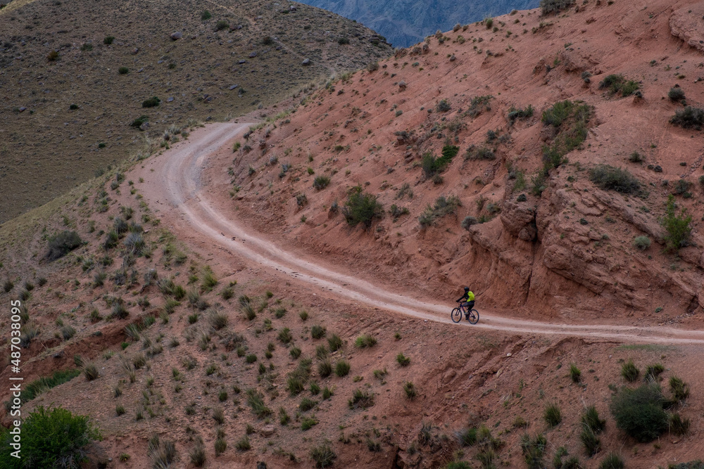 Cyclist is riding bicycle on gravel road in the mountains. Woman cycling MTB on gravel road trail track. Outdoor sport activity. Cyclist is riding bicycle on gravel road in the mountains. Woman cycling MTB on gravel road trail track. Outdoor sport activity.