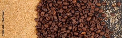 Scattered coffee beans and brown sugar on a black countertop.