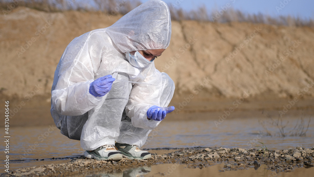 Scientist or ecology expert in protective costume analysis water from swamp, sample for toxicity testing. Scientific researching, field laboratory concept. Scientist or ecology expert in protective costume analysis water from swamp, sample for toxicity testing. Scientific researching, field laboratory concept.