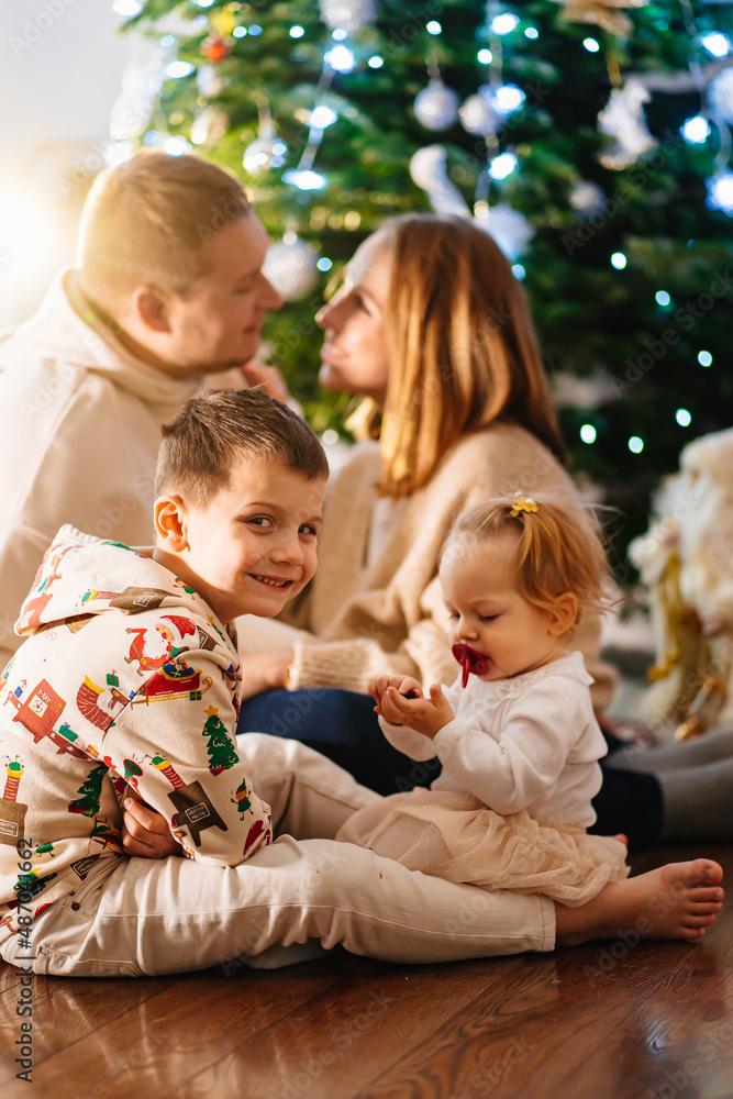 a happy family with two small children at home by the Christmas tree. a happy family with two small children at home by the Christmas tree.