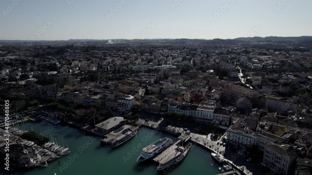 Aerial image filmed with a drone showing the town of Desenzano del Garda located on the shores of Lake Garda, northern Italy. Small port with sailing boats. Boats and yachts on the lake. Aerial image filmed with a drone showing the town of Desenzano del Garda located on the shores of Lake Garda, northern Italy. Small port with sailing boats. Boats and yachts on the lake.