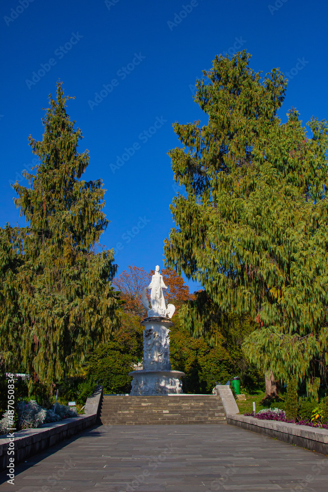 A large beautiful monument in antique style stands on a pedestal against a clear blue sky on a sunny day