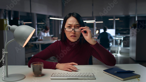 Canvas Print Shocked asian businesswoman looking at computer screen working late in office