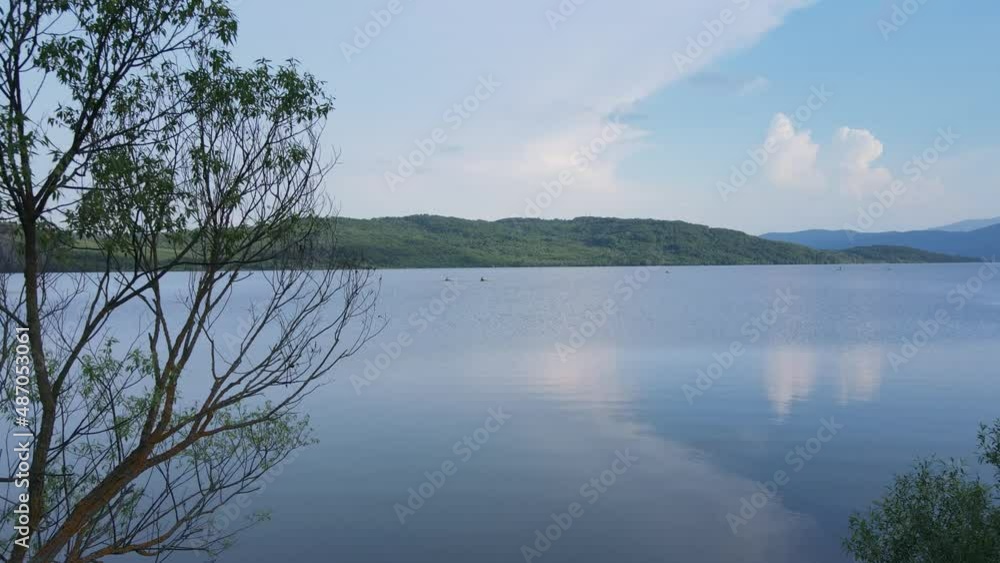 Flying from the shore to the water with a drone over the surface of a calm lake Flying from the shore to the water with a drone over the surface of a calm lake