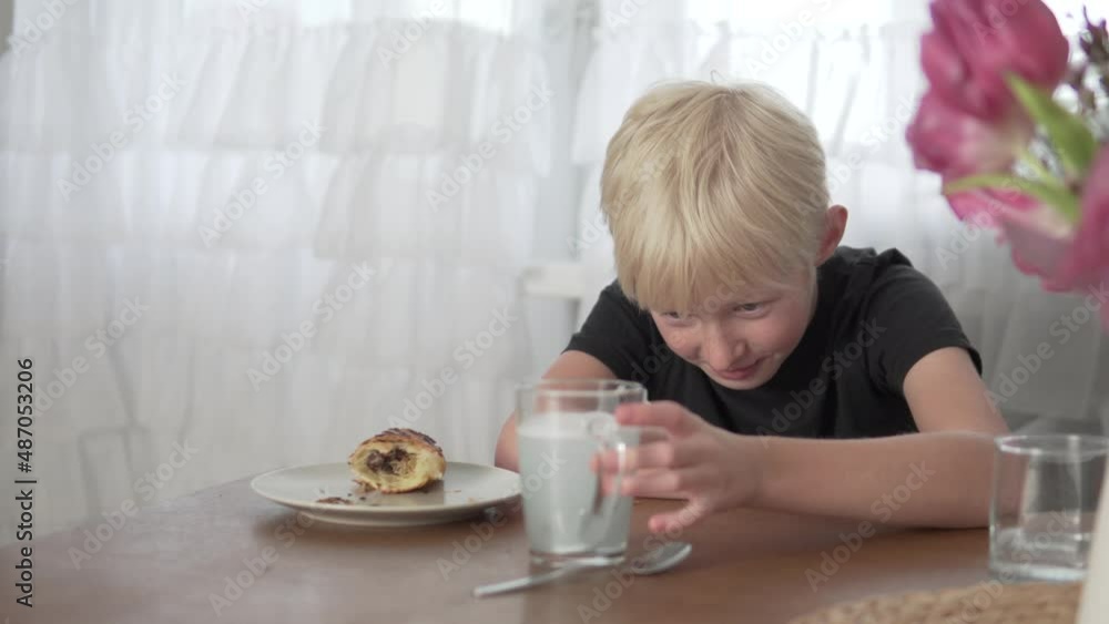 A blonde boy puts a denture in a glass of cleaning cloth before eating at home. A blonde boy puts a denture in a glass of cleaning cloth before eating at home.