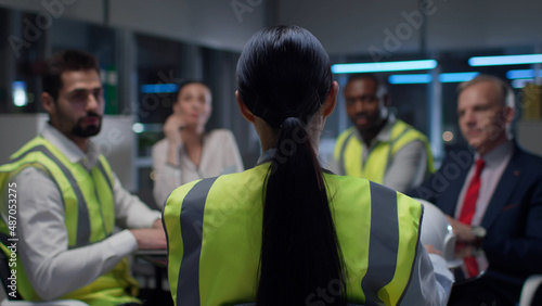 Back view of female engineer leading meeting with contractors in modern office