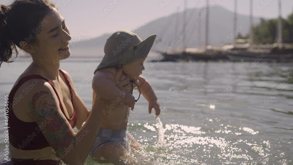 Happy young mom throws up baby in the pool. The development of kids ...