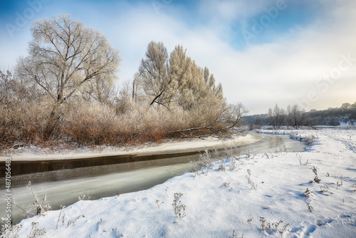 Beautiful Winter landscape scene background with snow covered trees and ice river.