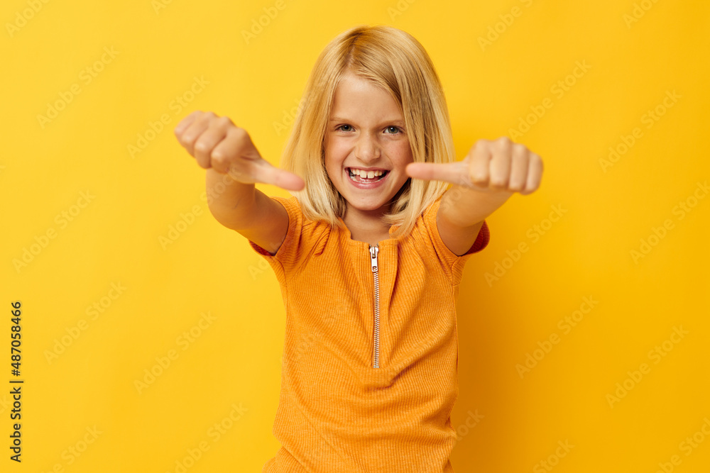 Young blonde girl in a yellow t-shirt smile posing studio childhood lifestyle unaltered Young blonde girl in a yellow t-shirt smile posing studio childhood lifestyle unaltered