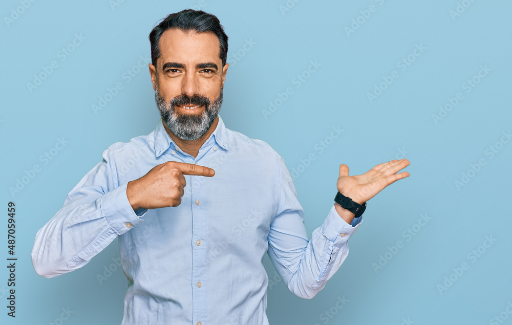 Middle aged man with beard wearing business shirt amazed and smiling to the camera while presenting with hand and pointing with finger. Middle aged man with beard wearing business shirt amazed and smiling to the camera while presenting with hand and pointing with finger.