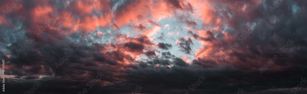 Dramatic dark sunset. Panorama of dark rain clouds in the evening. A rich red sky before a night thunderstorm