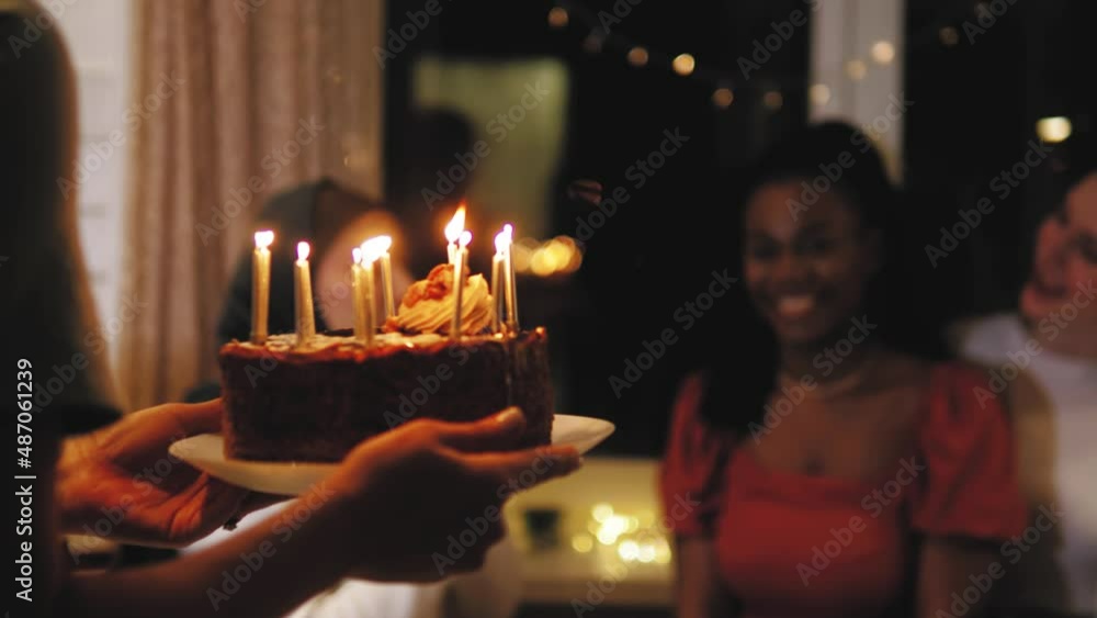 Happy african female having birthday blowing candles celebrating with multiracial female friends at night at home with lights, special event with friends Happy african female having birthday blowing candles celebrating with multiracial female friends at night at home with lights, special event with friends
