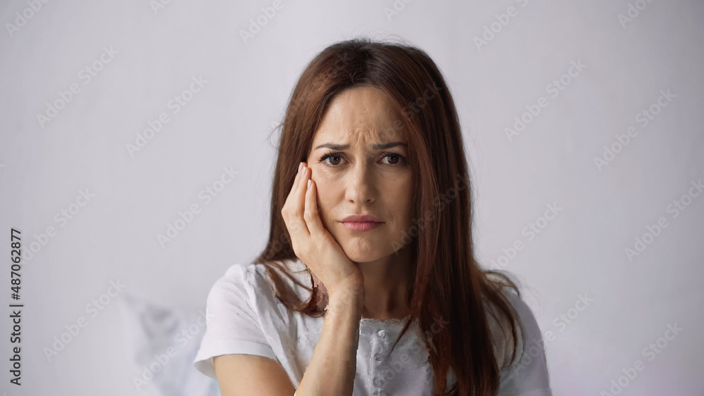displeased woman touching cheek while suffering from toothache on grey background displeased woman touching cheek while suffering from toothache on grey background