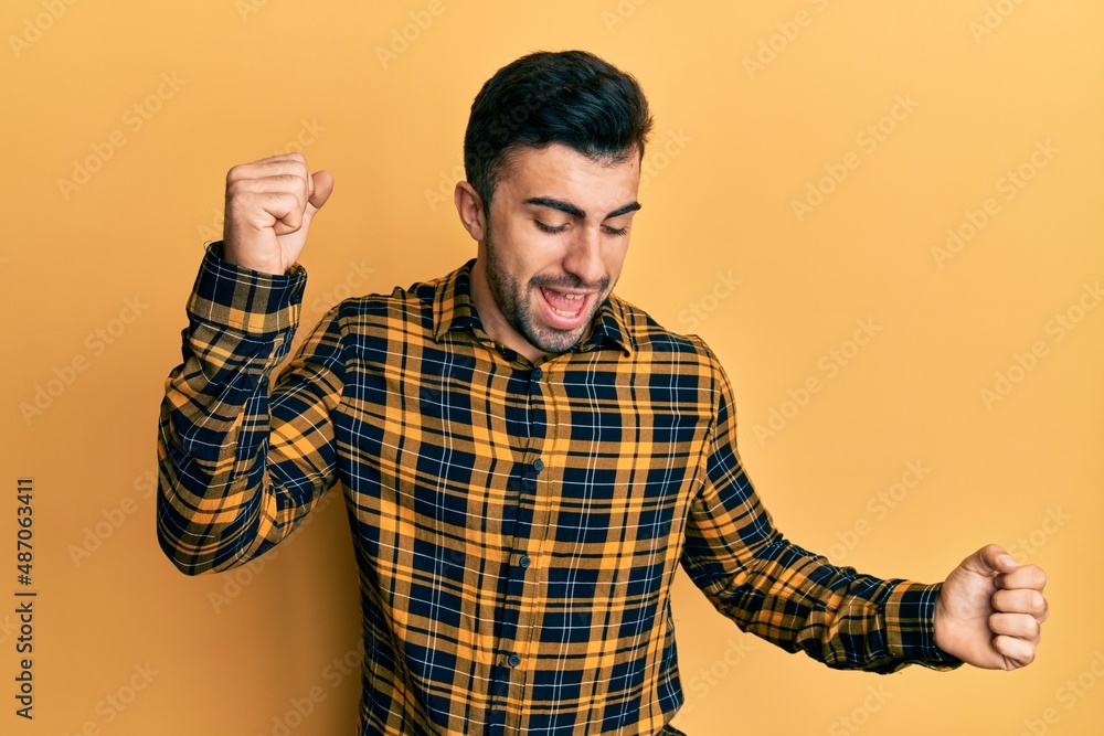 Young hispanic man wearing casual clothes dancing happy and cheerful, smiling moving casual and confident listening to music Young hispanic man wearing casual clothes dancing happy and cheerful, smiling moving casual and confident listening to music