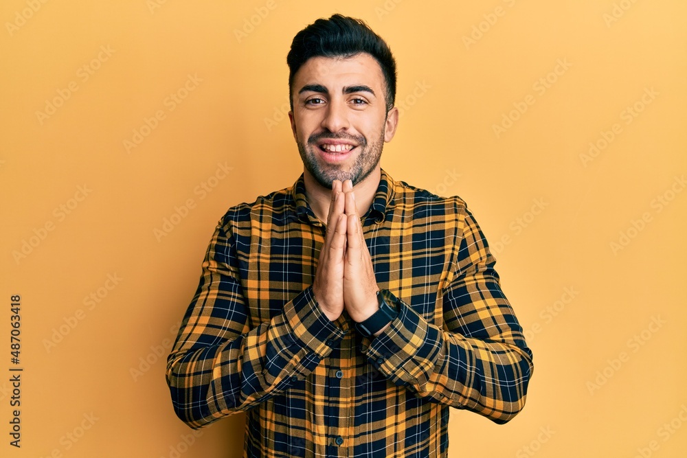 Young hispanic man wearing casual clothes praying with hands together asking for forgiveness smiling confident. Young hispanic man wearing casual clothes praying with hands together asking for forgiveness smiling confident.