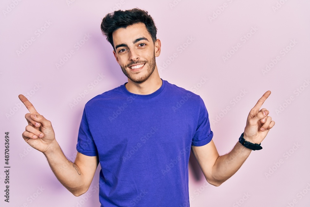 Young hispanic man wearing casual t shirt smiling confident pointing with fingers to different directions. copy space for advertisement Young hispanic man wearing casual t shirt smiling confident pointing with fingers to different directions. copy space for advertisement
