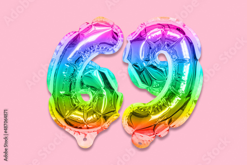 Rainbow foil balloon number, digit sixty nine on a pink background. Birthday greeting card with inscription 69. Top view. Numerical digit. Celebration event, template.