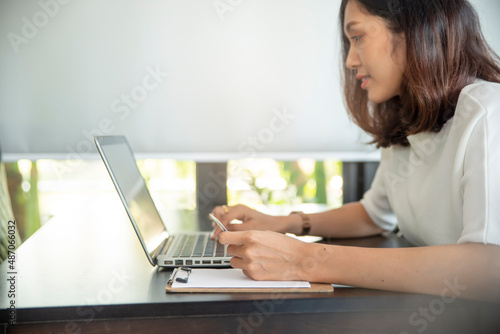 Asian woman holding credit card and using laptop to shopping online.Shopaholic girl selecting products to cart in online website And pay via internet banking.