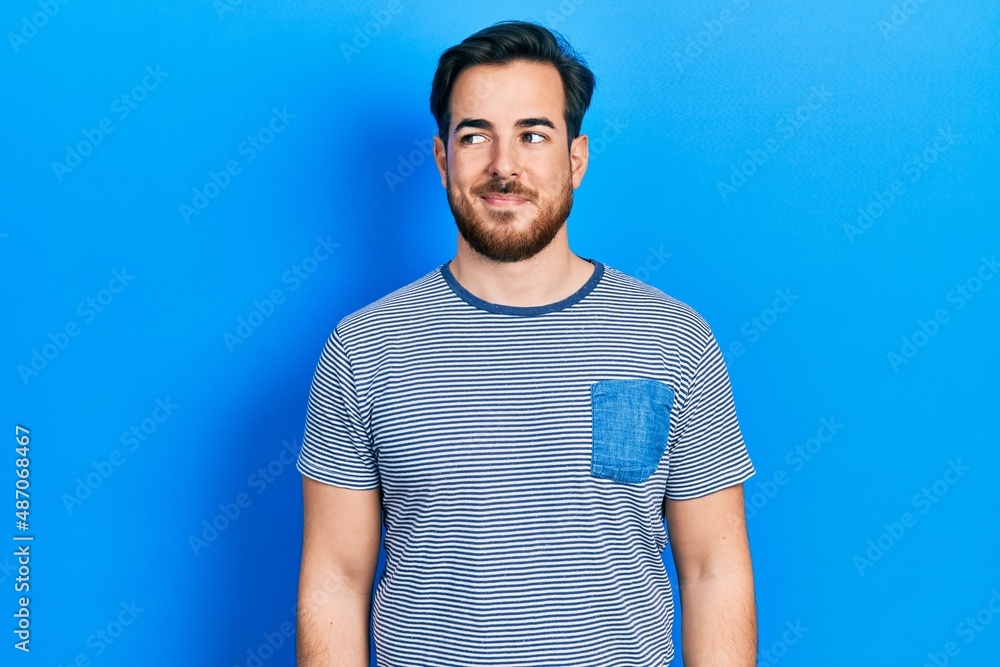 Handsome caucasian man with beard wearing casual striped t shirt smiling looking to the side and staring away thinking. Handsome caucasian man with beard wearing casual striped t shirt smiling looking to the side and staring away thinking.
