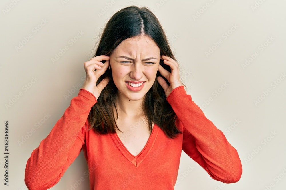 Young brunette woman wearing casual clothes covering ears with fingers with annoyed expression for the noise of loud music. deaf concept. Young brunette woman wearing casual clothes covering ears with fingers with annoyed expression for the noise of loud music. deaf concept.