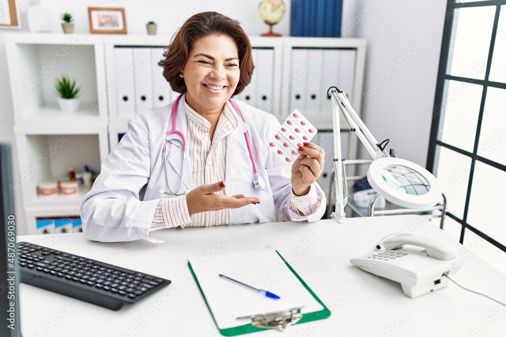 Middle age hispanic woman wearing doctor uniform holding pills at clinic Middle age hispanic woman wearing doctor uniform holding pills at clinic