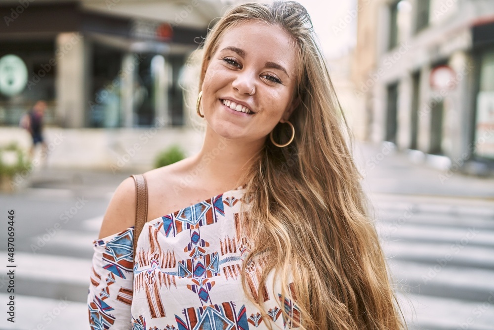 Young blonde girl smiling happy standing at the city.