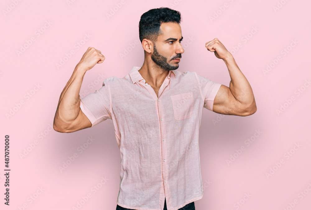 Hispanic man with beard wearing casual shirt showing arms muscles smiling proud. fitness concept. Hispanic man with beard wearing casual shirt showing arms muscles smiling proud. fitness concept.
